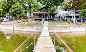 A wooden dock leading to a house with a covered porch and a staircase to a second level. - Spacious 4BR Lake House - LAKE VIEW - Rocky Mount (Rocky Mount)