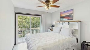 A bedroom with a bed, a ceiling fan, a window with a view, and a painting on the wall. - Charming lakefront Escape with Private Dock, Kayaks, and Beautiful Views (Eldon)