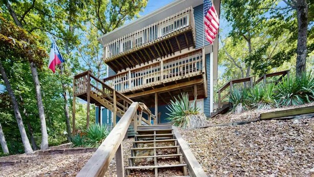 A two-story building with a wooden deck and a staircase leading to the entrance. - Charming lakefront Escape with Private Dock, Kayaks, and Beautiful Views (Eldon)
