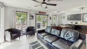 A modern living room with a leather sofa, a tufted armchair, and a dining area with a table and chairs. - Charming lakefront Escape with Private Dock, Kayaks, and Beautiful Views (Eldon)