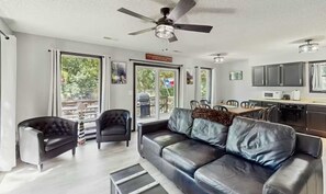 Ein modernes Wohnzimmer mit einer Ledersofa, einem Samt-Sessel und einem Essbereich mit Tisch und Stühlen.