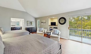 A bedroom with two beds, a TV, a desk, and a balcony with a railing.