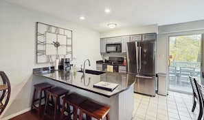 A modern kitchen with a central island, stainless steel appliances, and a large window.