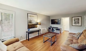 A living room with a sofa, a coffee table, a TV, and a painting on the wall.