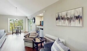 A modern living room with a sofa, chairs, a small table, and a large abstract painting.