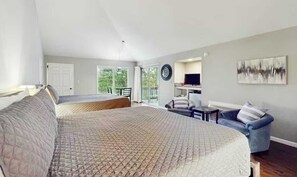 A bedroom with a large bed, a sofa, a TV, and a balcony.