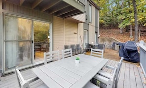 A patio with a table and chairs, a covered grill, and a sliding glass door.