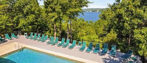 A pool area with lounge chairs and a view of a body of water.