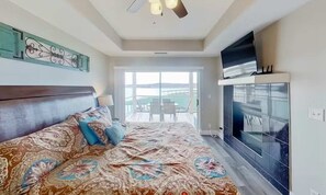 A bedroom with a large bed, a TV, and a balcony with a view. - Serene 3BR Condo - Lake Ozark - WATER VIEWS (Lake Ozark)
