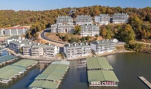 A waterfront hotel with multiple buildings, docks, and a forested hillside. - Serene 3BR Condo - Lake Ozark - WATER VIEWS (Lake Ozark)