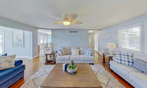 A living room with a ceiling fan, a sofa, a coffee table, and a dining area. - Serene 5BR Lake Home - LAKE VIEW - Sunrise Beach (Sunrise Beach)