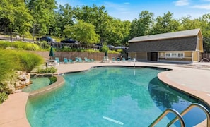 A swimming pool with lounge chairs and a building in the background. - Rustic 5BR House - Dock & POOL - Margaritaville (Osage Beach)