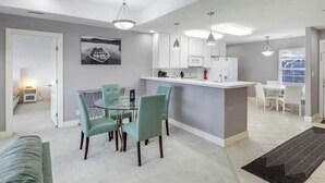 Una cucina moderna con mobili bianchi, un'isola centrale e luci a sospensione.