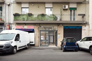 A building with a ground-level entrance, a balcony with plants, and a blue garage door. - A cozy 75 sqm apartment on two levels, ideal for up to 4 people, located on the ground floor of a building (with internal stairs to the upper level).The property is located in a residential area of ​​Catania, a short walk from the seafront and about  (Catania)