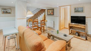 A living room with a sofa, a table, a TV, and a staircase leading to another room. - Holiday Home 'Romo 1' with Mountain View (Chavida)