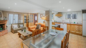 A modern kitchen with a dining area, a sofa, and a fireplace. - Holiday Home 'Romo 1' with Mountain View (Chavida)