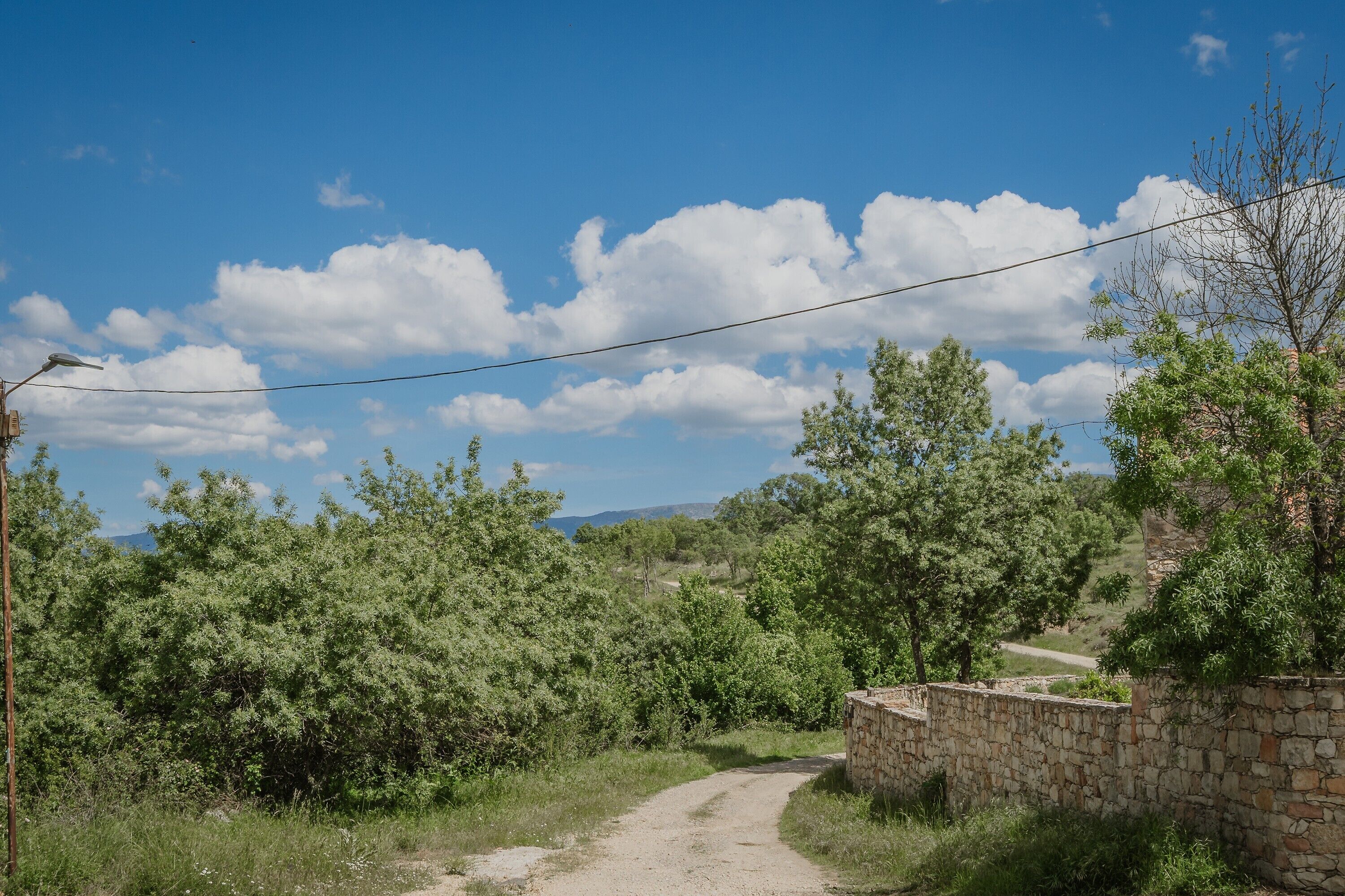 A rural road with stone walls and trees.