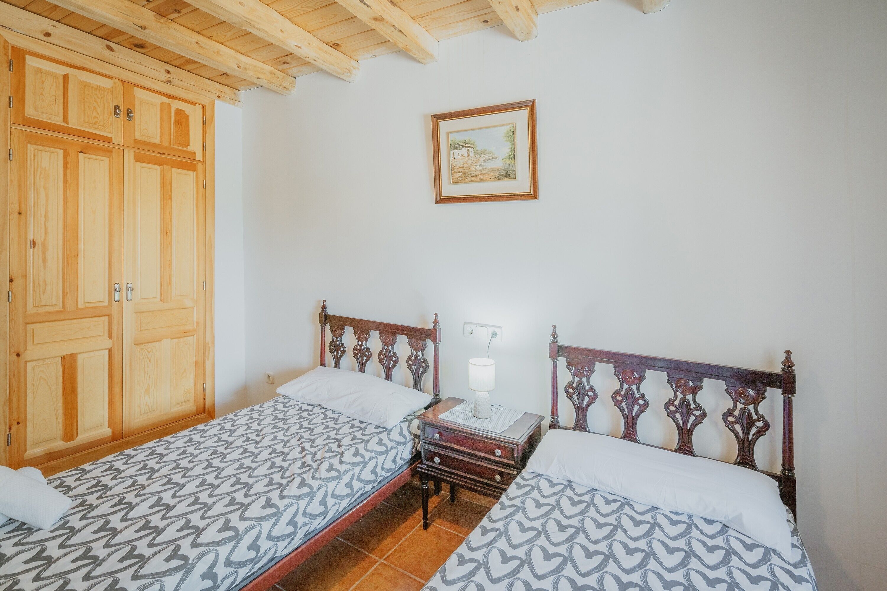Un dormitorio con dos camas, un armario de madera y un cuadro enmarcado en la pared.