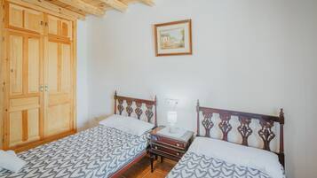 Un dormitorio con dos camas, un armario de madera y un cuadro enmarcado en la pared.