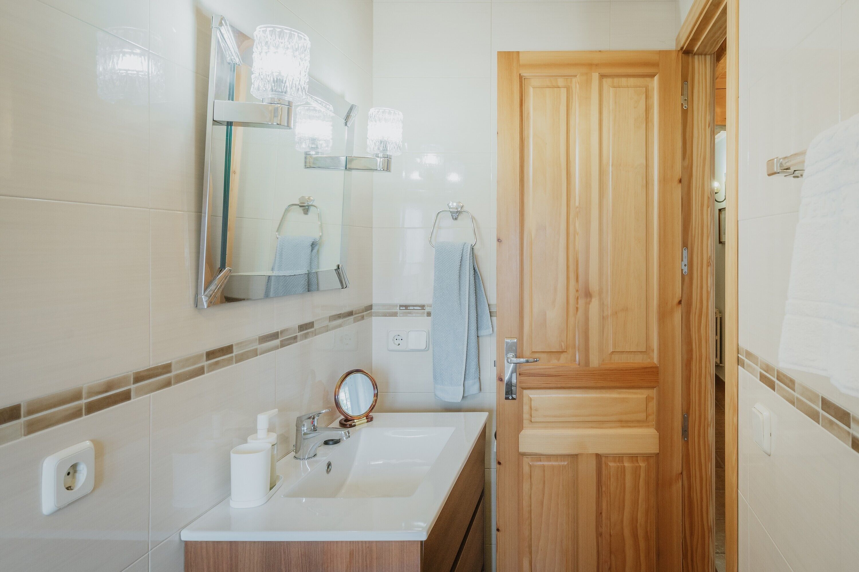 Une salle de bain avec un lavabo, un miroir et une porte en bois.