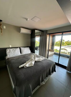 Ein modernes Hotelzimmer mit einem großen Bett, einer Klimaanlage, Blick ins Freie und einem Balkon.