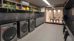 Eine moderne Küche mit integrierten Waschmaschinen, einem Essbereich mit Stühlen und einem Blumentopf auf der Arbeitsfläche.