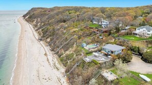 A coastal property with a beach, houses, and a large building with a green roof.