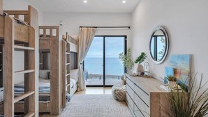 A bedroom with a bunk bed, a large window with a view, a dresser, and a mirror.