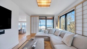 Een moderne woonkamer met een ruime hoekbank, een flatscreen televisie en een schuifpui die uitkomt op een balkon met uitzicht.