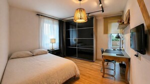 Un dormitorio con cama, escritorio con silla, televisor y armario corredero.