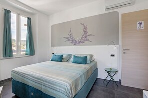 Ein Schlafzimmer mit einem Bett, einem kleinen Tisch, einer Wand-Klimaanlage und einer Tür.