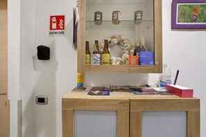 Ein Empfangstresen mit einer Glasvitrine, die Flaschen, ein пожарzeichen, ein gerahmtes Bild und verschiedene Gegenstände auf der Theke enthält.