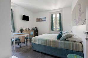A bedroom with a bed, a desk, a chair, a TV, and a window with curtains. - Apartment 'Bilocale - Lavanda e Salvia' with Wi-Fi and Air Conditioning (La Spezia)