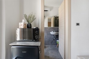 A compact kitchen with a microwave, a small refrigerator, and a vase with dried plants. - Room - Rosmarino with Balcony, Wi-Fi and Air Conditioning (La Spezia)