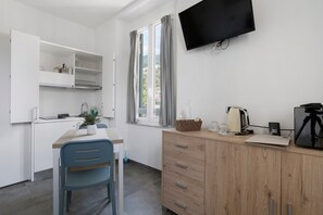 A compact kitchen with a dining area, a TV mounted on the wall, and a window with curtains. - Studio Apartment 'Monolocale - Timo' with Wi-Fi and Air Conditioning (La Spezia)