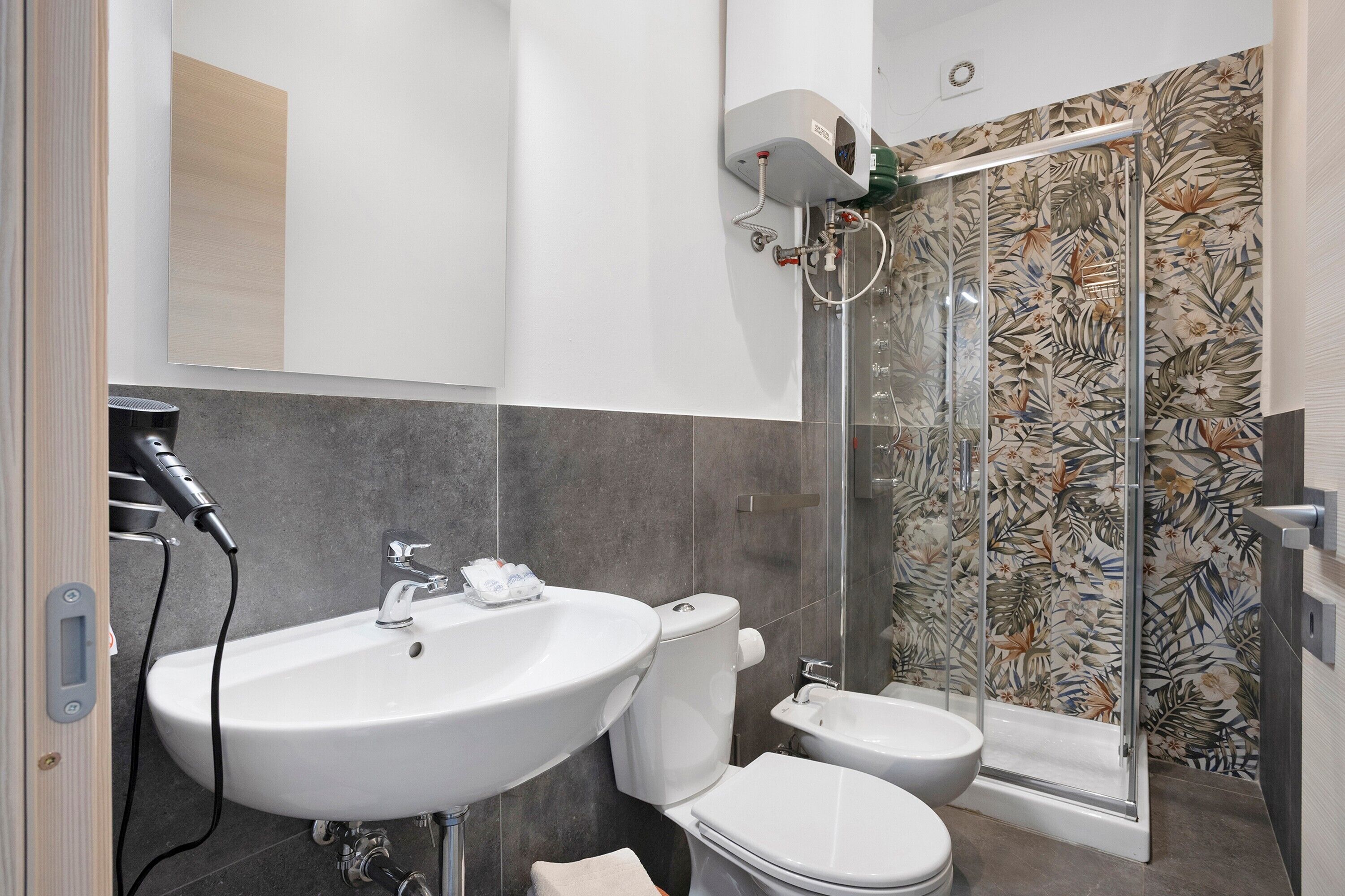 Une salle de bain équipée d’un lavabo, de toilettes, d’un bidet et d’une douche avec une porte en verre.