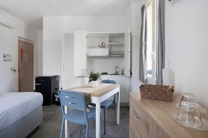 A compact room with a bed, a small kitchenette, a dining table with chairs, and a window. - Studio Apartment 'Monolocale - Timo' with Wi-Fi and Air Conditioning (La Spezia)