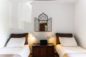 A bedroom with two beds, a nightstand with a lamp, a dresser, and a decorative mirror on the wall. - L'Océan - Au calme de la Campagne (Saint-Martin-de-Hinx)