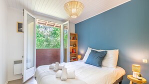Een slaapkamer met een bed, een nachtkastje met een lamp, een boekenplank en een schuifdeur naar een buitenruimte.