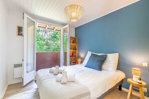 Une chambre à coucher comprenant un lit, une table de chevet avec une lampe, une bibliothèque et une porte-fenêtre coulissante donnant sur un espace extérieur.