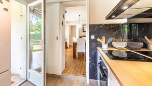 Een moderne keuken met een zwarte marmeren spatwand, roestvrijstalen apparatuur en een eethoek die door een open deur zichtbaar is.