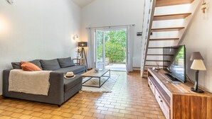 Een woonkamer met een bank, salontafel, televisie en een trap.