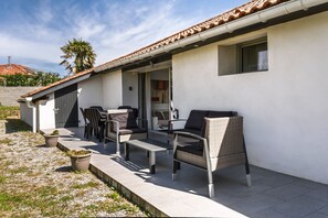 A patio with outdoor furniture, a small table, and potted plants. - La Campagne - Bel appartement avec terrasse (Saint-Martin-de-Hinx)