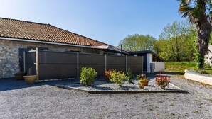 Une maison avec une façade en pierre, un toit en tuiles et une allée gravillonnée.