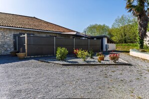 A house with a stone facade, a tiled roof, and a gravel driveway. - La Campagne - Bel appartement avec terrasse (Saint-Martin-de-Hinx)