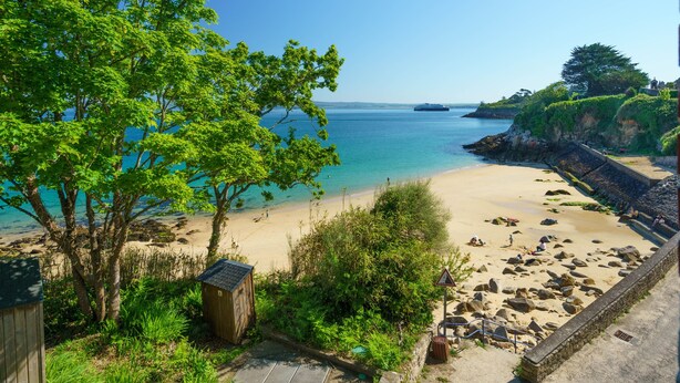 Ein Strand mit klarem, blauem Wasser, einem sandigen Ufer und einer kleinen Holzkonstruktion.