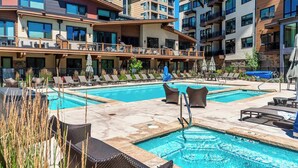 Un hotel con zona de piscina, varios balcones y mobiliario exterior.