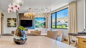 Una sala de estar moderna con un ventanal grande, un comedor y un televisor.