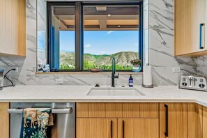 A modern kitchen with a large window, a stainless steel sink, and wooden cabinets. - Lux Beaver Creek Escape | Views & Resort Amenities (Avon)