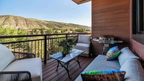 Balcón con vista a las montañas, una parrilla y mobiliario.